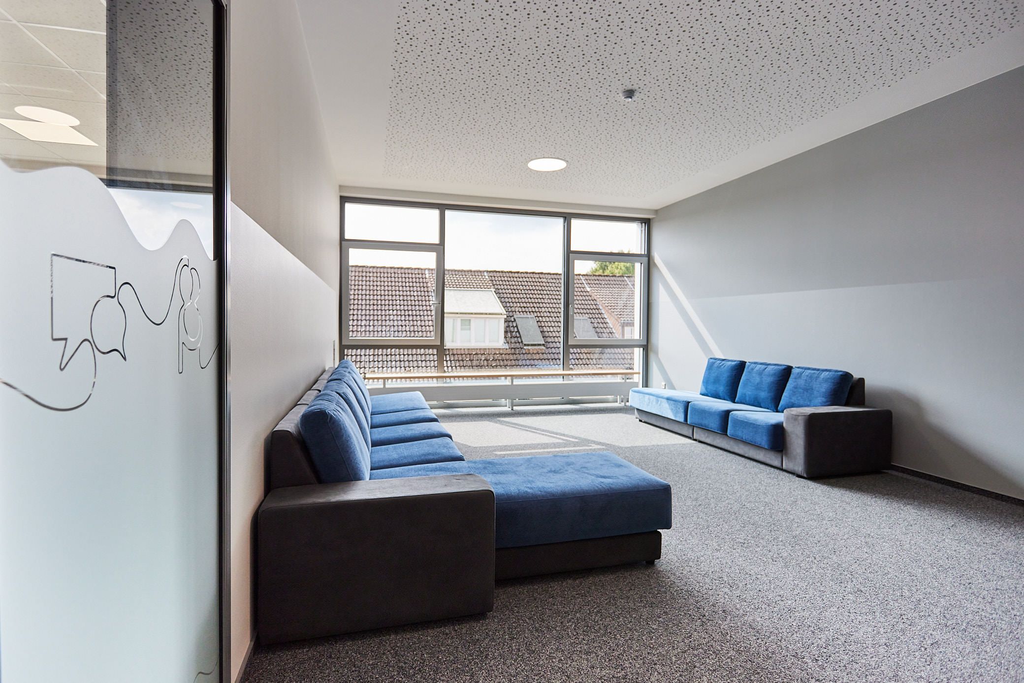 Großer Loungebereich. Großes Fenster, blaue Sofas. Ein Projekt von EPU ARCHITEKTEN.
