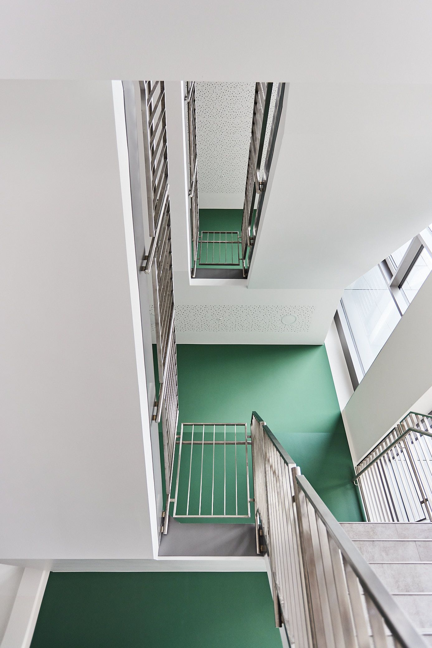 Treppenhaus. Grüne Wände. Metallhandlauf. Ein Projekt von EPU ARCHITEKTEN.