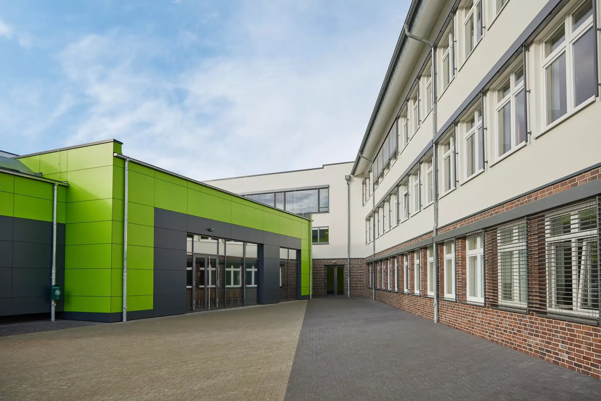 Innenhof. Schulgebäude, Klinkerfassade, grüne HPL-Platten. Ein Projekt von EPU ARCHITEKTEN.