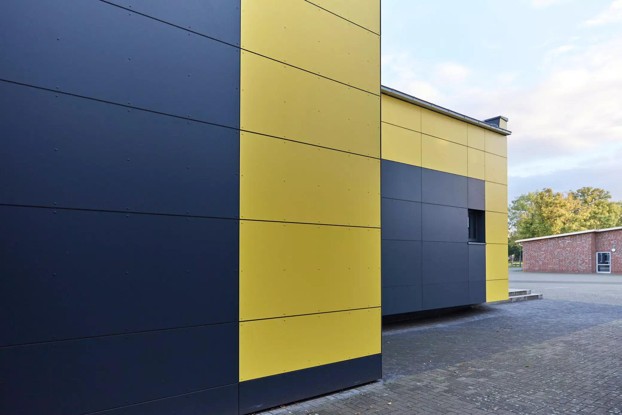 Schulgebäude, Klinkerfassade, gelbe Trespa-Platten. Ein Projekt von EPU ARCHITEKTEN.