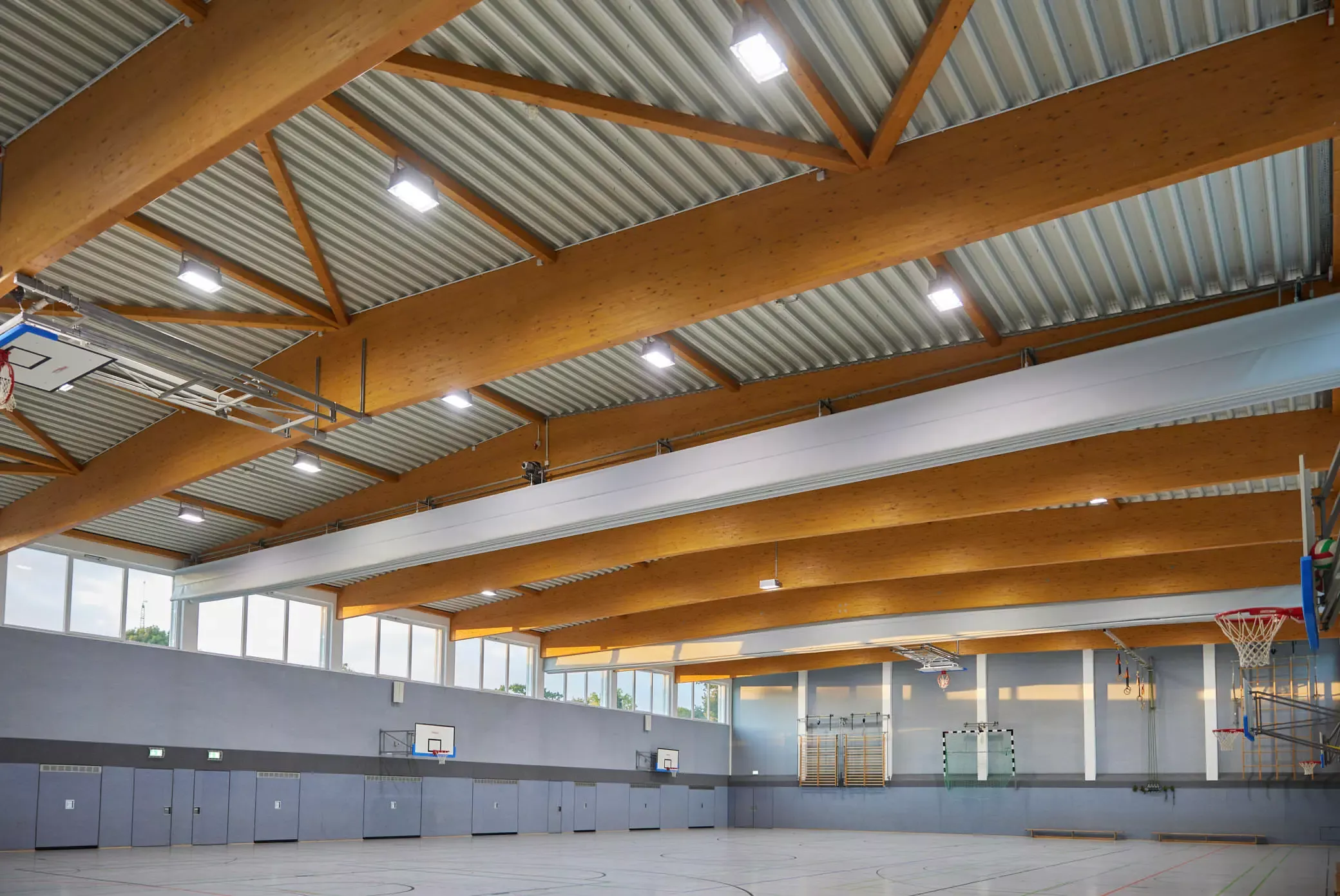 Sporthalle der Gesamtschule Minden. Holzkonstruktion der Decke. Basketballkörbe. Das Projekt ist geplant von EPU ARCHITEKTEN.
